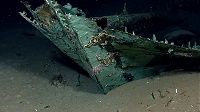 The copper-sheathed hull on one of the Monterrey wrecks serves as protection against marine-boring organisms in the wood beneath the waterline. The copper has turned green due to oxidation and chemical processes over more than a century on the seafloor. Oxidized copper sheathing and possible draft marks are visible on the bow of the ship. Credit: NOAA Okeanos Explorer Program