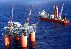Photo of a platform with two rigs and a drilling boat