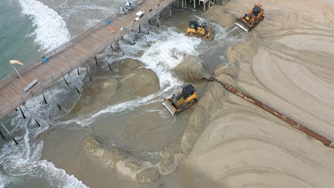Bulldozers relocate OCS sand around an OBX pier in 2022.