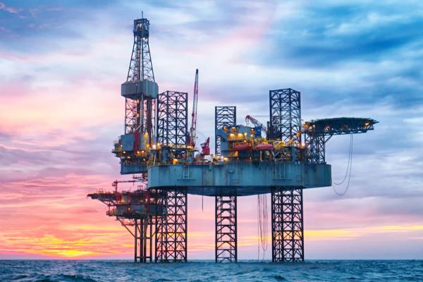 Ocean going "Jack Up" rig dominates the foreground against a pink and orange crepuscular time in the background
