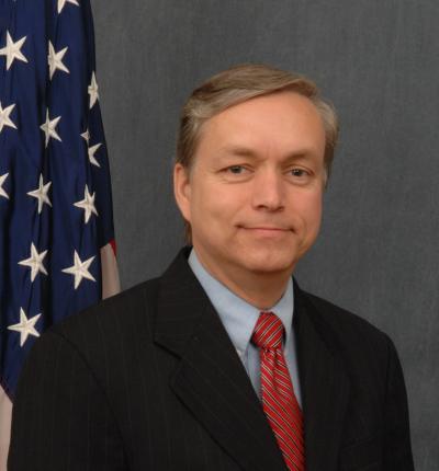 Headshot photo of Walter Cruickshank with the American flag in the background