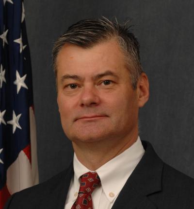 Headshot photo of James Anderson with the American flag in the background