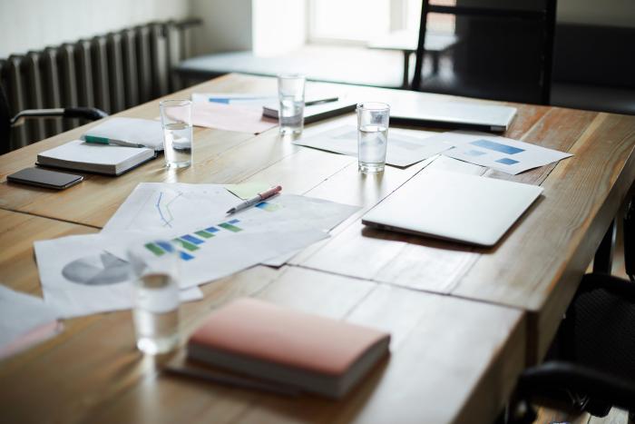 Background image of modern office interior with documents on wooden table in conference room