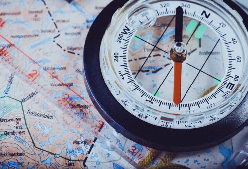 A handheld plastic compass on top of a map