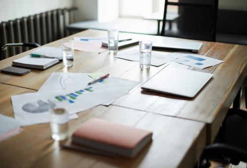 Background image of modern office interior with documents on wooden table in conference room