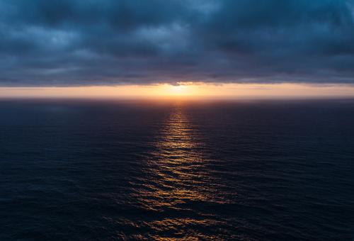 Sunlight piercing the dark blue clouds on the atlantic ocean